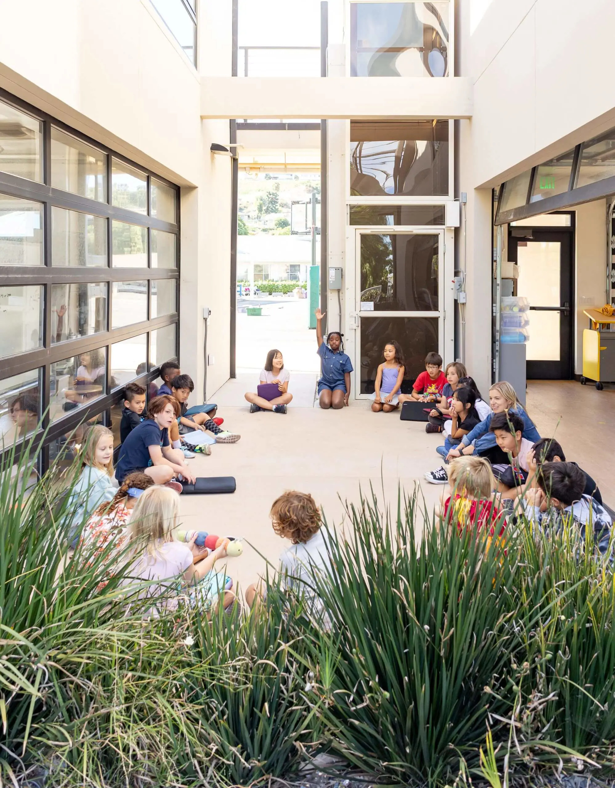 Village students sit in a circle for their morning meeting in the outdoor classroom in the Innovation and Design Building.