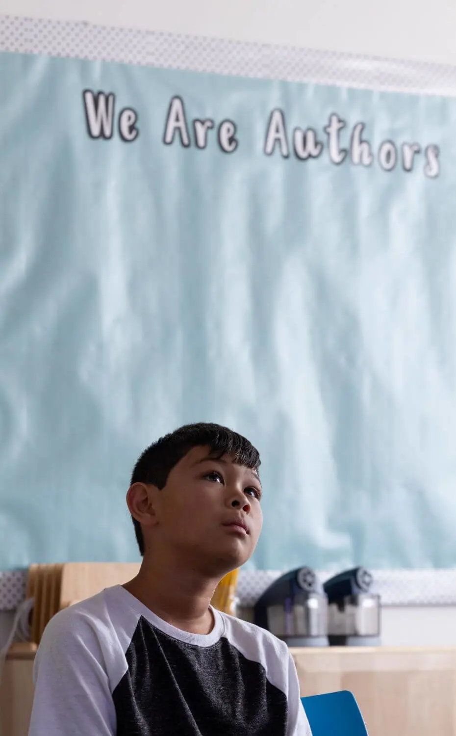 Chadwick student sits in front of a bulletin board that reads, “We are authors.”