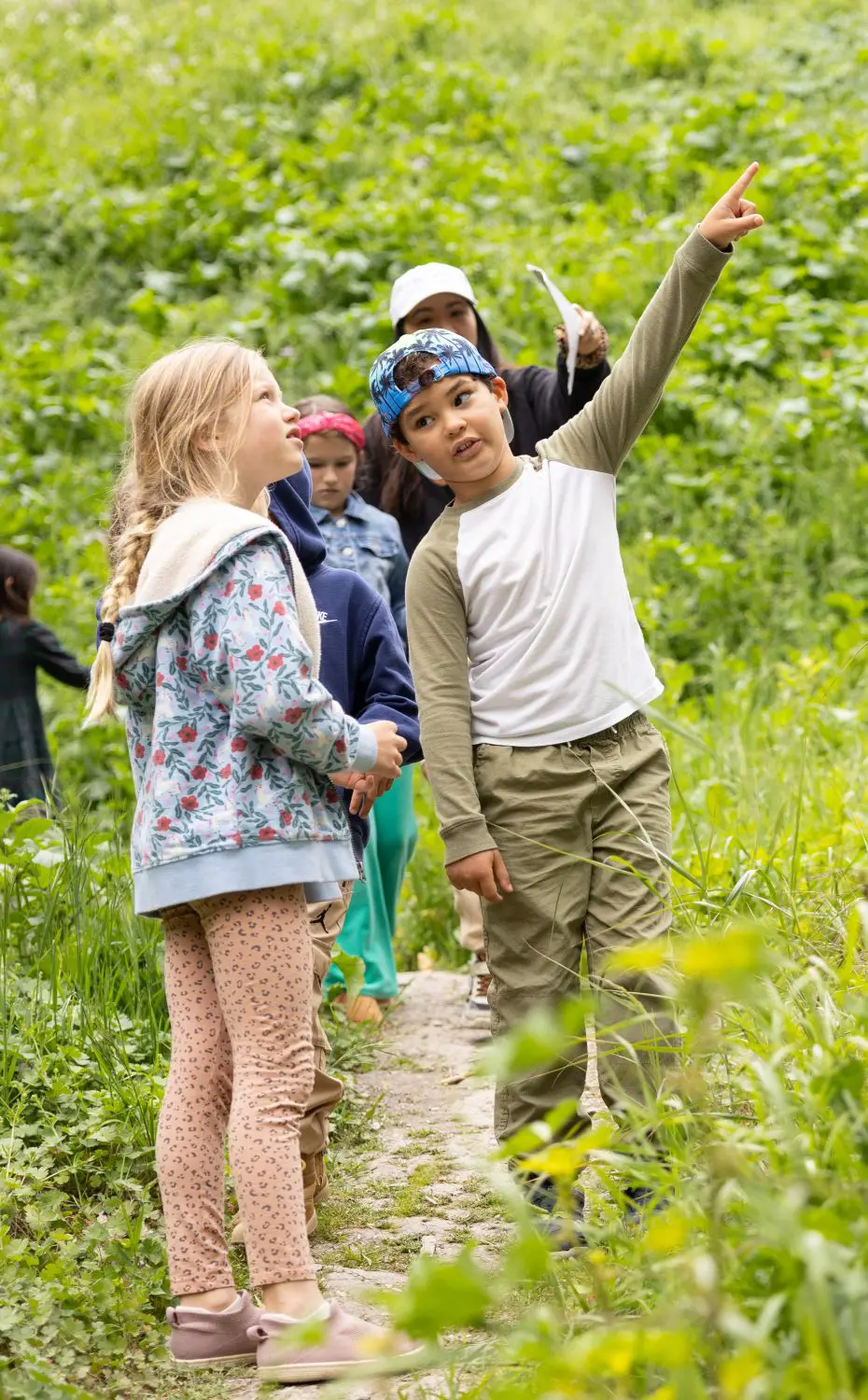 Student points off into the distance while on a hike with his classmates.