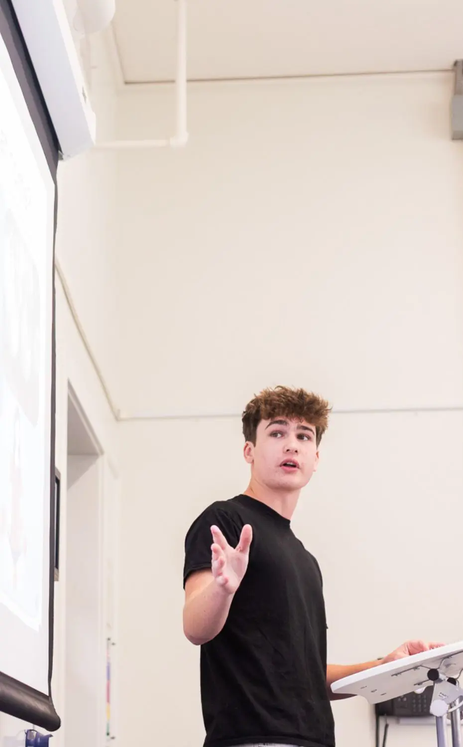 Chadwick Upper School student gestures while giving a presentation in front of a projected slideshow.