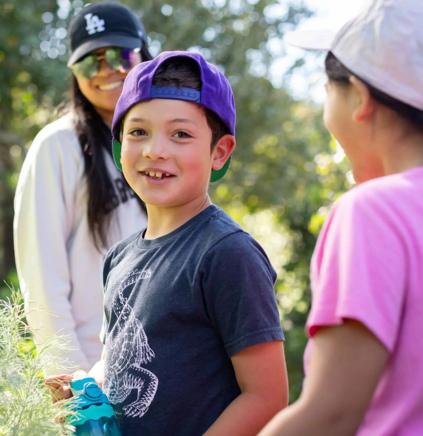 A Village student in a purple hat smiles while on a hike with his class in the Chadwick Canyon.