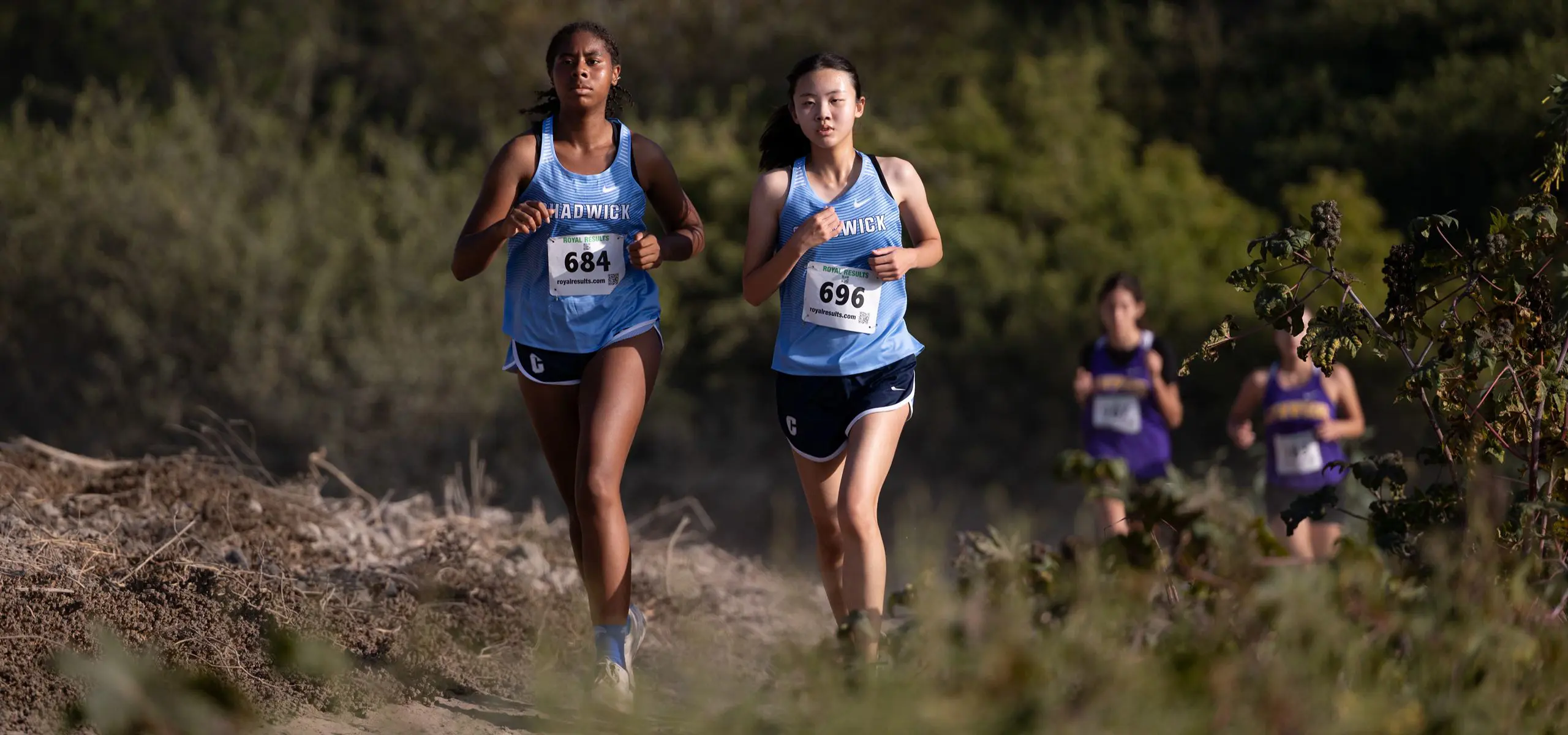 Two Chadwick Girls Cross-Country runners run alongside each other during a meet. 