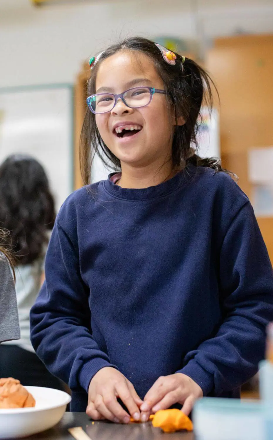 Village School student grinning while creating a model of a volcano during a science class.