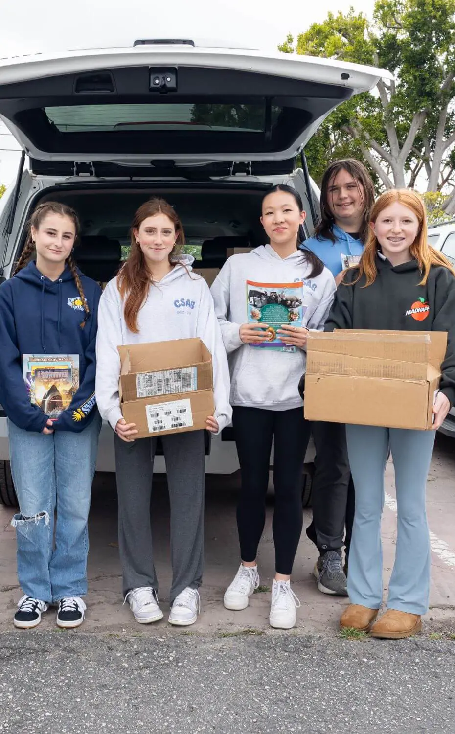 Middle School students loading boxes of books into a car to donate them to an Elementary School in need. 