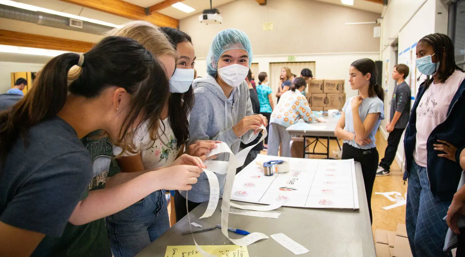 8th Grade students labelling Rise Against Hunger boxes at the Middle School day of service.