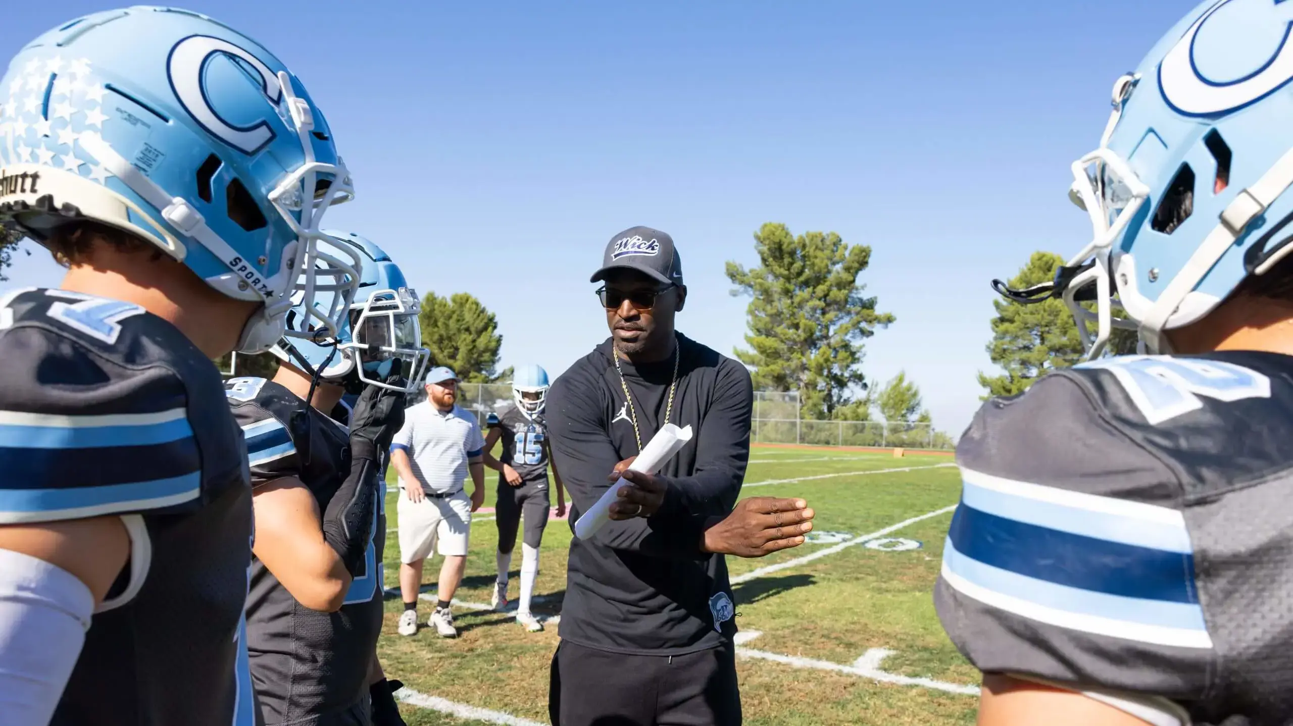 Coach discussing game strategy with student Football players.