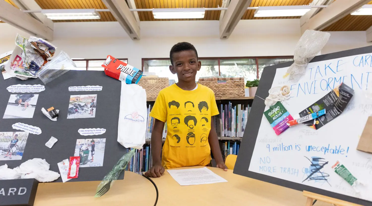 A Chadwick student stands in front of their visual project display on sustainability.