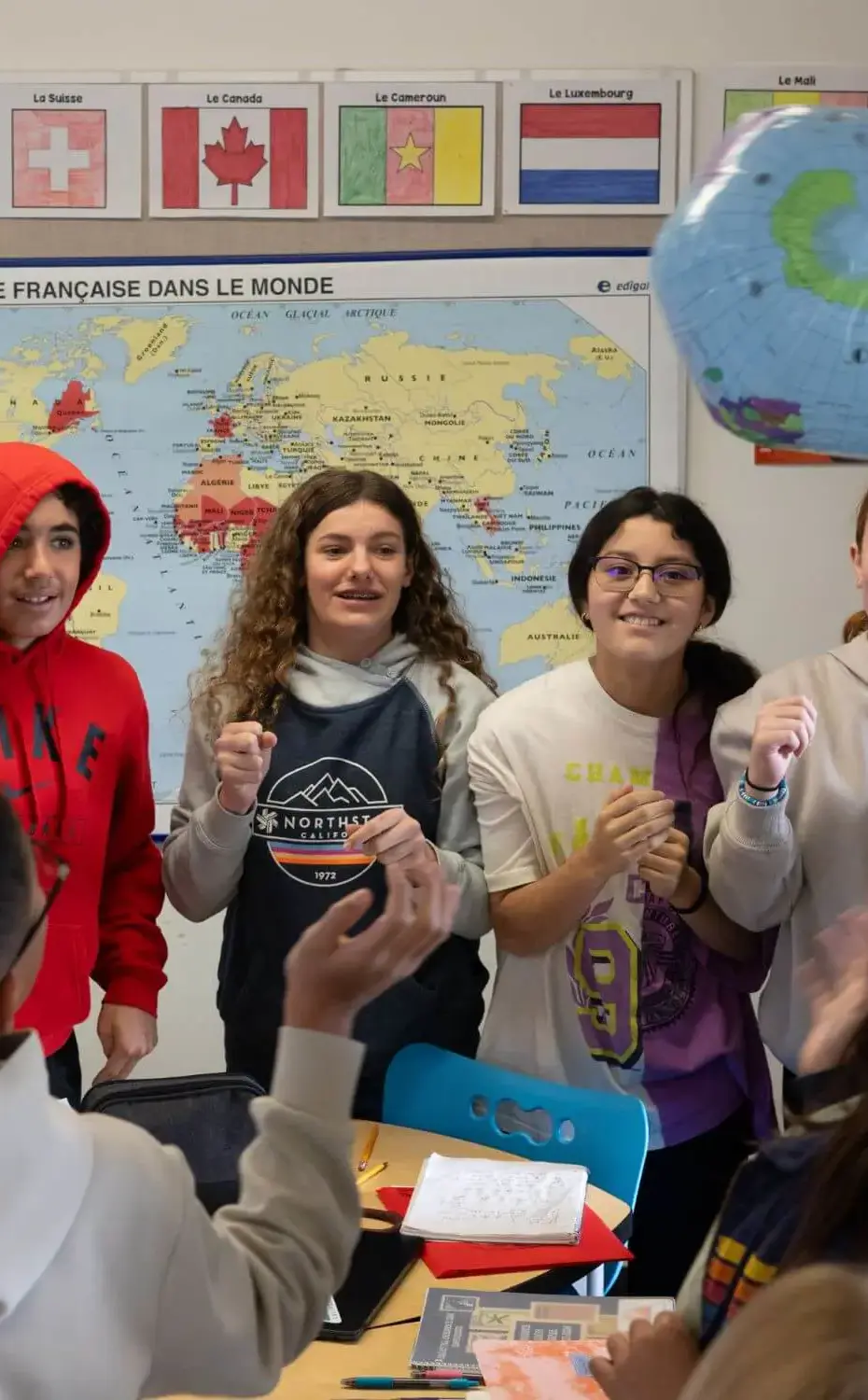 Students stand in a circle hitting an inflatable globe in a game during Spanish class.