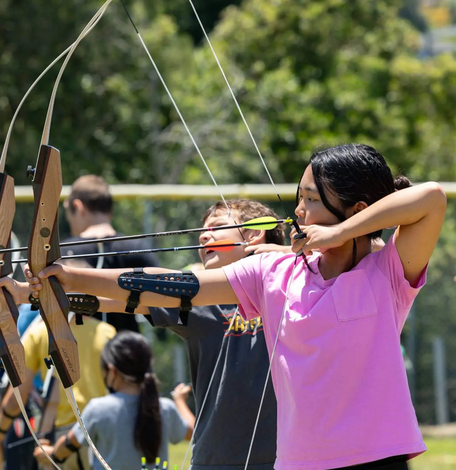 Girls aim their bow and arrows at camp.