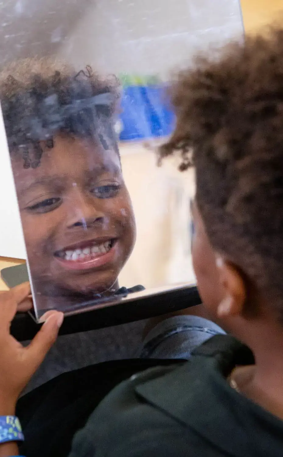 Student smiles at themself while looking in a mirror.